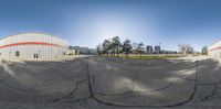 a panorama of a vacant parking lot and surrounding structures in the sun at daytime from inside