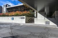 an empty city street under a pedestrian covered overpassed by concrete walls and fences