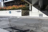 an empty city street under a pedestrian covered overpassed by concrete walls and fences