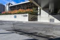 an empty city street under a pedestrian covered overpassed by concrete walls and fences