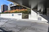 an empty city street under a pedestrian covered overpassed by concrete walls and fences