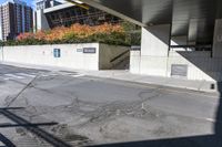 an empty city street under a pedestrian covered overpassed by concrete walls and fences