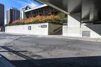 an empty city street under a pedestrian covered overpassed by concrete walls and fences