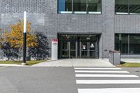 the entry of a brick building with glass doors on it and a pedestrian crossing area below