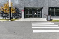 the entry of a brick building with glass doors on it and a pedestrian crossing area below