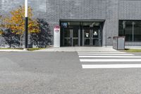 the entry of a brick building with glass doors on it and a pedestrian crossing area below