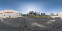 a panorama of a vacant parking lot and surrounding structures in the sun at daytime from inside