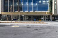 an empty street in front of a building that looks like a hotel or store with large glass windows