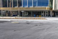 an empty street in front of a building that looks like a hotel or store with large glass windows