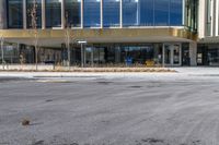 an empty street in front of a building that looks like a hotel or store with large glass windows