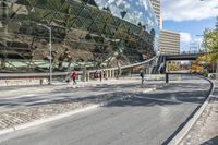 several pedestrians are walking on an empty street near the modern building and sky scrapes