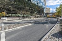 several pedestrians are walking on an empty street near the modern building and sky scrapes