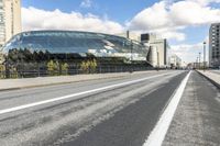 a road with some cars on it next to some buildings and a blue sky with clouds