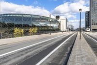 a road with some cars on it next to some buildings and a blue sky with clouds