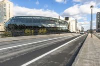 a road with some cars on it next to some buildings and a blue sky with clouds