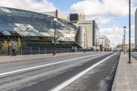 a road with some cars on it next to some buildings and a blue sky with clouds