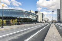 a road with some cars on it next to some buildings and a blue sky with clouds