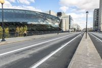 a road with some cars on it next to some buildings and a blue sky with clouds