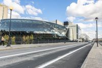 a road with some cars on it next to some buildings and a blue sky with clouds