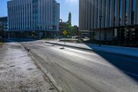 an empty street with two yellow traffic signs and some tall buildings on a sunny day