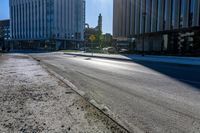 an empty street with two yellow traffic signs and some tall buildings on a sunny day