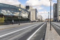 an empty city street with a big glass building behind it and traffic on either side