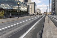 an empty city street with a big glass building behind it and traffic on either side