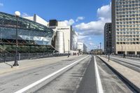 an empty city street with a big glass building behind it and traffic on either side