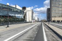 an empty city street with a big glass building behind it and traffic on either side