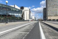 an empty city street with a big glass building behind it and traffic on either side