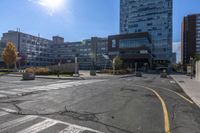 a large empty intersection with buildings in the background on a sunny day with sunshine flares