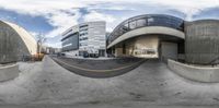 a fish eye lens captures a curved building and a parking garage in the middle of it