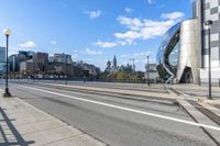 an empty city street with a sidewalk and a person walking across it that has a crosswalk in front of the intersection