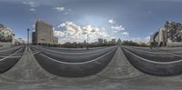 a fish eye lens shot of some buildings and clouds in the background, and a sky with many clouds