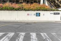 the traffic light is near a very high wall with some signs written in front of it