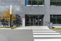 a street has a white crosswalk in front of an office building with two tall windows