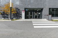 a street has a white crosswalk in front of an office building with two tall windows