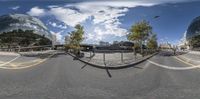 an upside down fish eye image of an empty city road with many trees and the building behind it