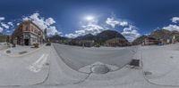 a fisheye lens view of a town with mountains in the distance and blue sky