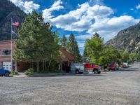 a big house with two fire trucks parked next to it and mountains in the background