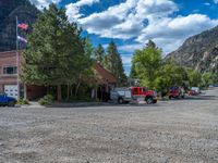 a big house with two fire trucks parked next to it and mountains in the background