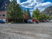 a big house with two fire trucks parked next to it and mountains in the background