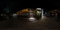 an outdoor bar and restaurant lit up at night in the dark city of europe, europe