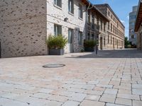 this is an outdoor brick floor with a drain on it in front of two buildings