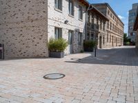 this is an outdoor brick floor with a drain on it in front of two buildings