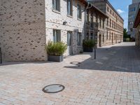 this is an outdoor brick floor with a drain on it in front of two buildings