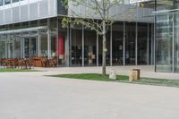 a paved area with tables and chairs, outside of a building with glass windows and doors