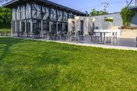 an outside area with several tables and chairs on the grass and a building next to it