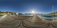 a fish eye view of an outdoor dock next to the water with a boat dock in the background