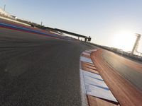 a view of an outdoor stadium racing track and bridge during the day of daylight with one runner on the side